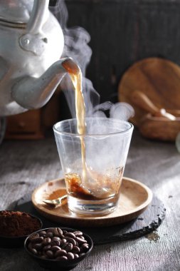 Bardağa doldurulan bir fincan kahve.