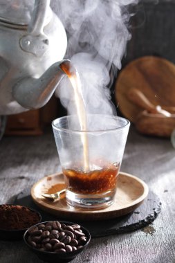 Bir fincan kahve dolduran bir çaydanlık.