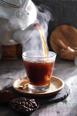 Bardağa doldurulan bir fincan kahve.