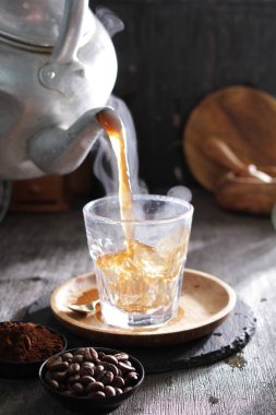 Bardağa doldurulan bir fincan kahve.