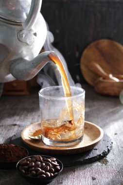 Bardağa doldurulan bir fincan kahve.