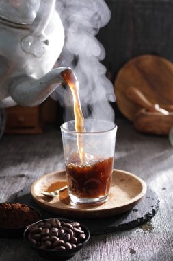 Bardağa doldurulan bir fincan kahve.