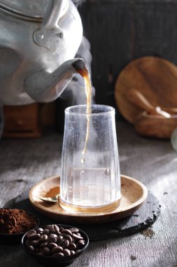 Bardağa doldurulan bir fincan kahve.