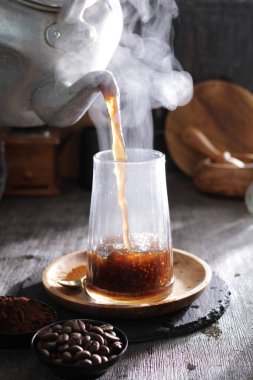 Bardağa doldurulan bir fincan kahve.