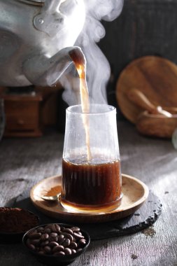 Bardağa doldurulan bir fincan kahve.