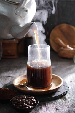 Bardağa doldurulan bir fincan kahve.