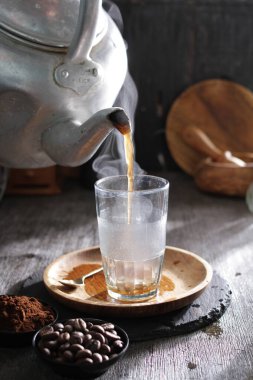 Bardağa doldurulan bir fincan kahve.