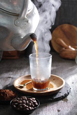 Bardağa doldurulan bir fincan kahve.