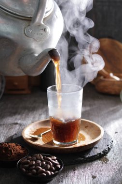 Bardağa doldurulan bir fincan kahve.