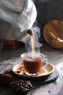 Çaydanlığa bir fincan kahve dökülüyor.