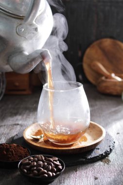 Bir çaydanlık bardağa çay dolduruyor.