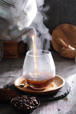 Bir çaydanlık bardağa çay dolduruyor.