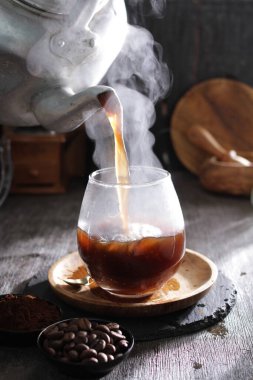 Bir çaydanlık bardağa çay dolduruyor.