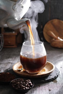 Bardağa doldurulan bir fincan kahve.