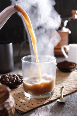 Biri bardağa kahve dolduruyor.