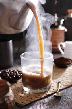 Biri bardağa kahve dolduruyor.