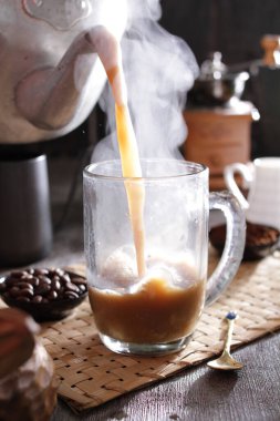 Biri cam bardağa kahve dolduruyor.