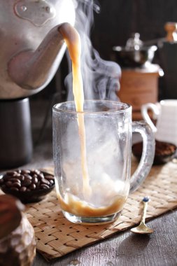 Biri cam bardağa kahve dolduruyor.