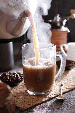 Bir insan bardağa bir fincan kahve dolduruyor.