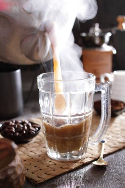 Biri cam bardağa kahve dolduruyor.