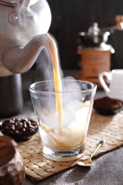 Bir insan bardağa bir fincan kahve dolduruyor.