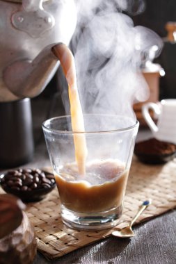 Bardağa doldurulan bir fincan kahve.