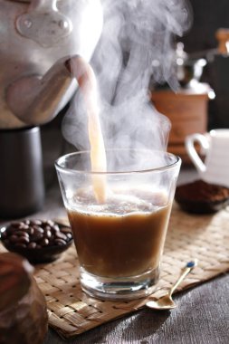 Bardağa doldurulan bir fincan kahve.