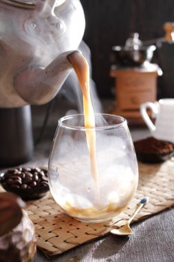 Bir insan bardağa bir fincan kahve dolduruyor.