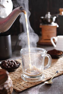 Bardağa doldurulan bir fincan kahve.