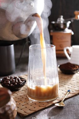 Biri bardağa kahve dolduruyor.