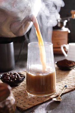 Biri bardağa kahve dolduruyor.