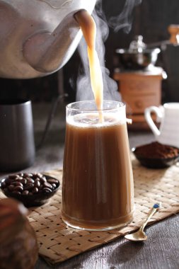 Bir insan bardağa bir fincan kahve dolduruyor.