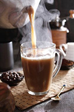 Bir insan bardağa bir fincan kahve dolduruyor.