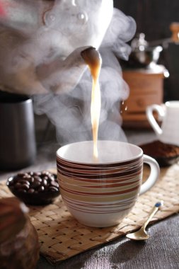 Masanın üzerinde dumanı tüten bir fincan kahve.