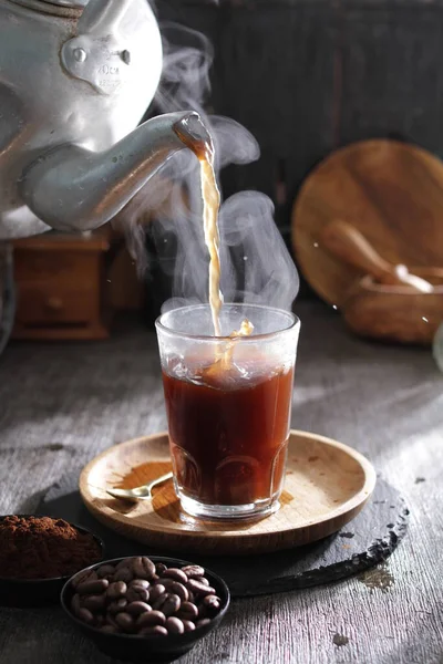 Bardağa doldurulan bir fincan kahve.