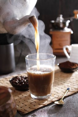 Bardağa doldurulan bir fincan kahve.