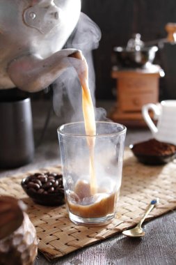 Bir insan bardağa bir fincan kahve dolduruyor.