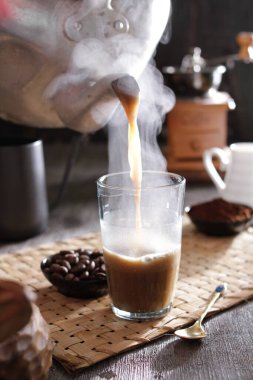 Biri bardağa kahve dolduruyor.