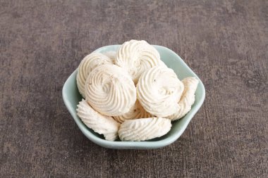 Masanın üzerinde bir kase beyaz kurabiye.