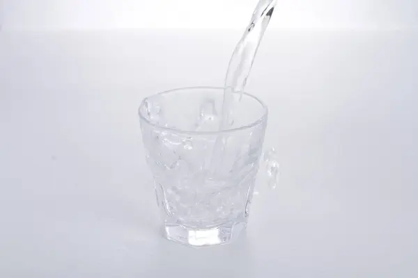a glass of water being poured into a cup