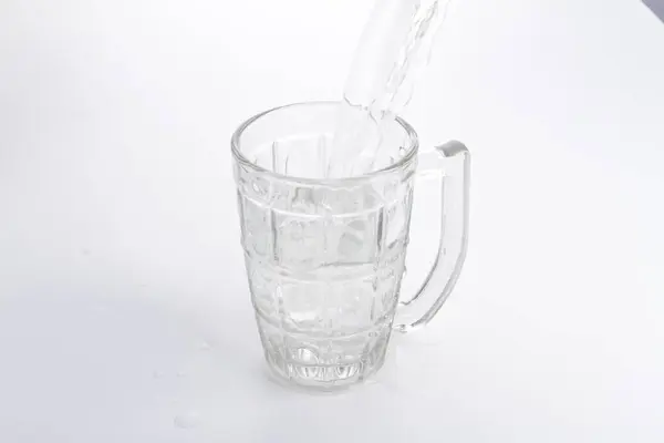 a glass of water being poured into a pitcher