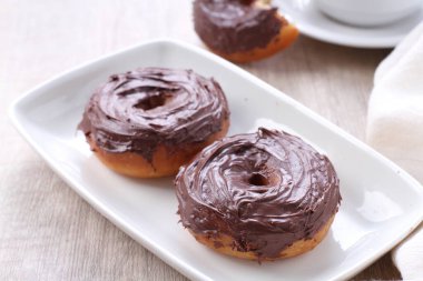 Beyaz tabakta iki çikolatalı donut.