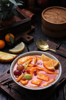 Bir kase meyve çorbası, bir kaşık ve bir kase portakal.