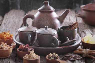 bir çaydanlık, çay fincanı, ve ahşap bir masada diğer yiyecek parçaları.