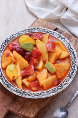 Kesme tahtasında bir kase meyve ve sebze.