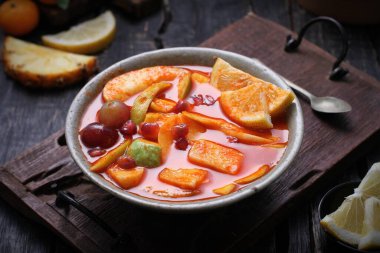 Kesme tahtasında bir kase meyve ve sebze.