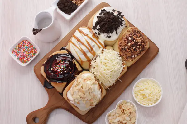 Kremalı ve fındıklı çikolatalı çörekler ahşap masada.