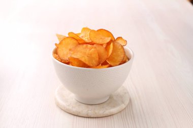 Beyaz tabakta bir kase patates cipsi