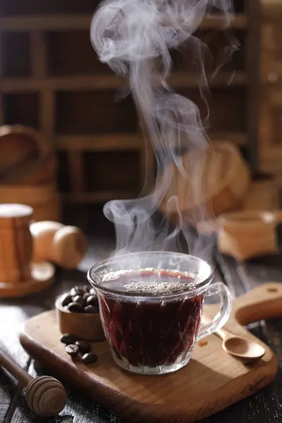 hot tea in the cup with steam and smoke on a wooden table.