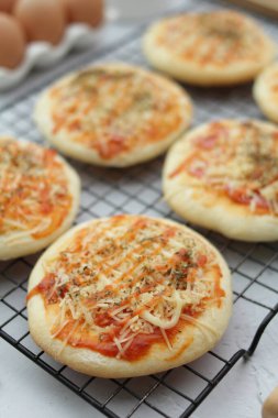 Beyaz tabakta domates, soğan ve peynirli ev yapımı pizza.